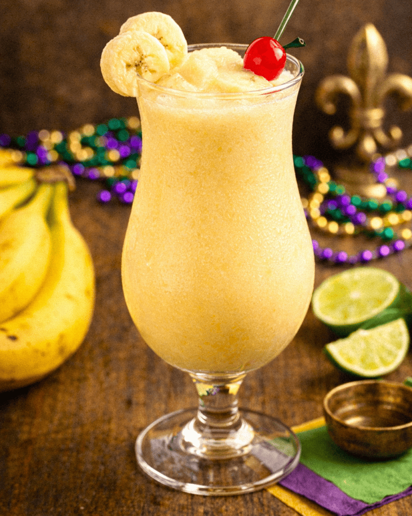 Tropical banana and lime smoothie with cherry garnish in a tall glass.