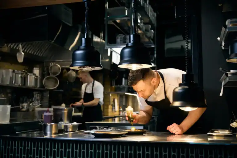 Professional chef plating food in a modern restaurant kitchen.