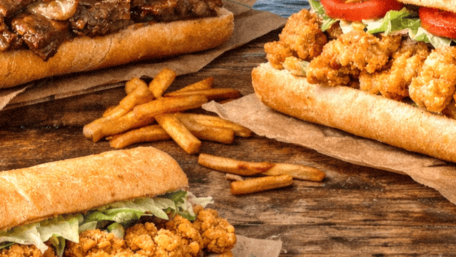 A delicious assortment of Po'boys from Louisiana with crispy fries on a rustic wooden table by the river as we discover Louisianas best Po'boys.
