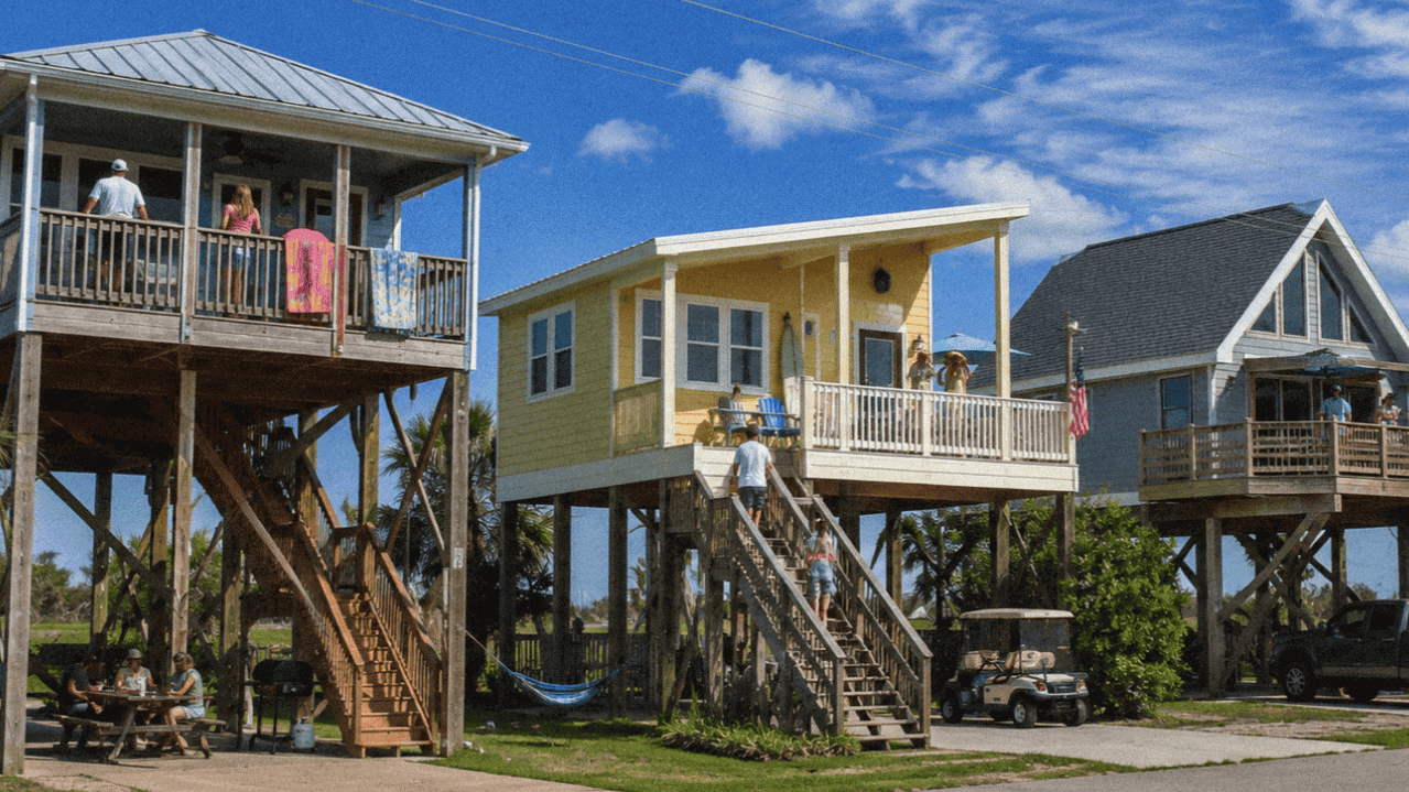 Colorful stilt houses by the water with outdoor decks in Louisiana and vibrant surroundings.