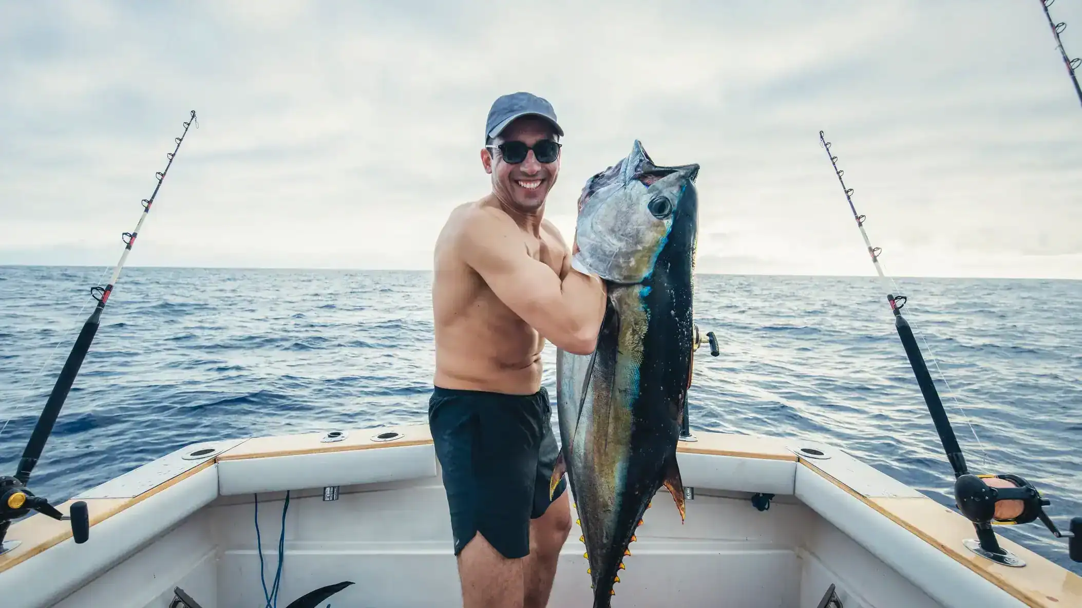 A large tuna fish caught off the coast of Louisiana on a boat during a fishing trip with a man holding it proudly.