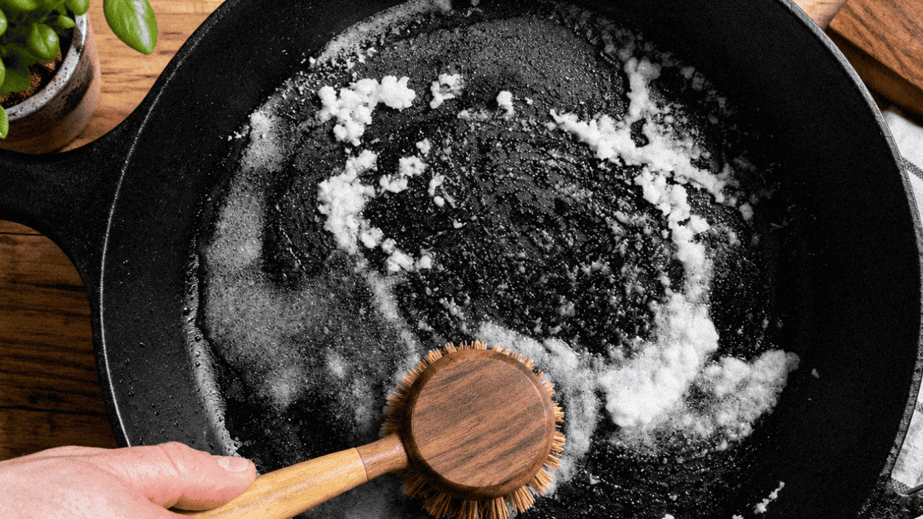 Cast iron skillet with salt and a wooden spoon on a wooden surface, Louisiana cooking scene.