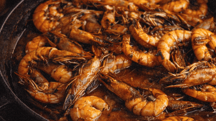 Succulent shrimp cooked in flavorful sauce served in a cast iron skillet with toasted bread slices.